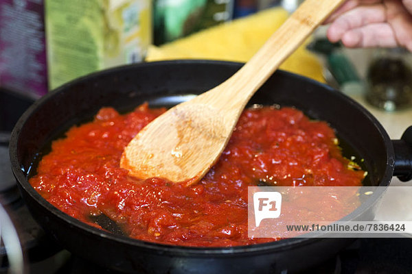 Tomato sauce in frying pan with wooden spatula