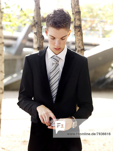 A serious young businessman text messaging on his smart phone
