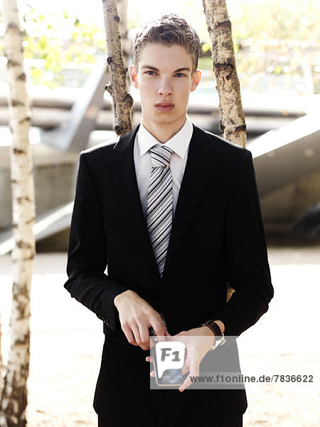 A young businessman holding a smart phone and looking serious