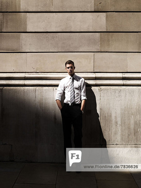A young handsome businessman leaning against a building