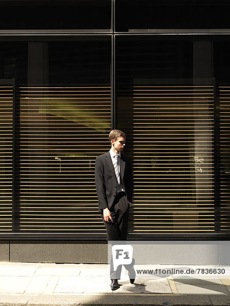 A young businessman standing outside a building  looking away
