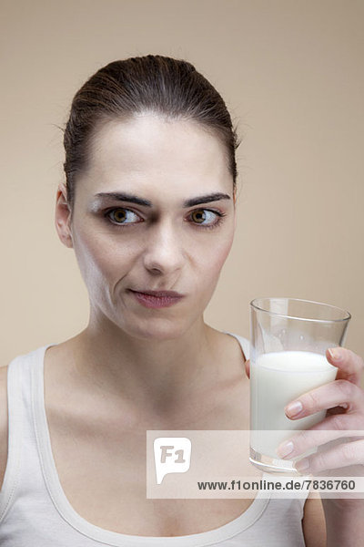 Eine junge Frau  die ein Gesicht macht  nachdem sie einen Schluck Milch getrunken hat.