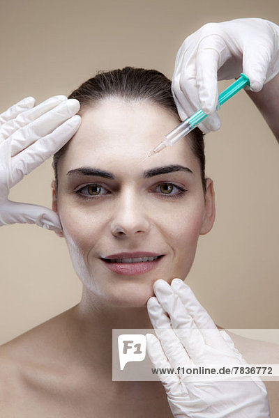 Eine lächelnde junge Frau  die Botox-Injektionen erhält.