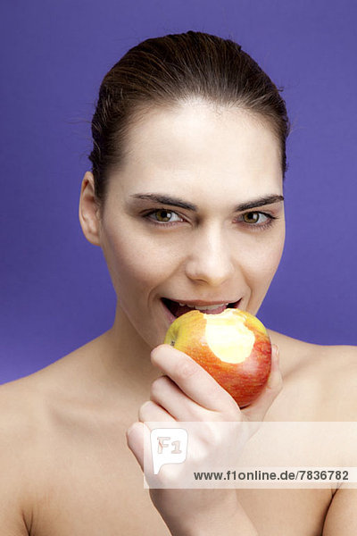 Eine lächelnde junge Frau beim Apfelessen