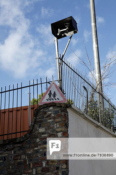 Niederwinkelansicht einer an einem Zaun befestigten Videoüberwachungskamera