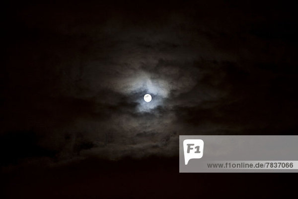 The full moon seen in the sky surrounded by clouds