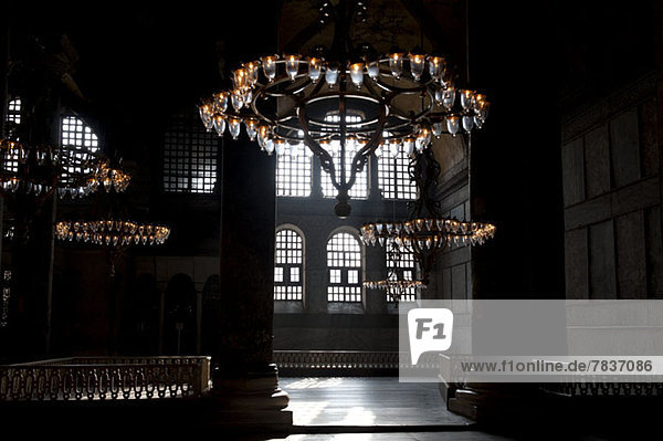 Chandeliers hanging in a shadowed interior of the Blue Mosque  Istanbul  Turkey