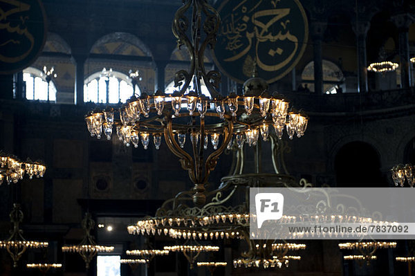 Chandeliers hanging in the Blue Mosque  gold Arabic script in background  Istanbul  Turkey
