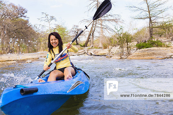 USA  Texas  Junge Frau beim Kajakfahren auf dem Frio River  lächelnd