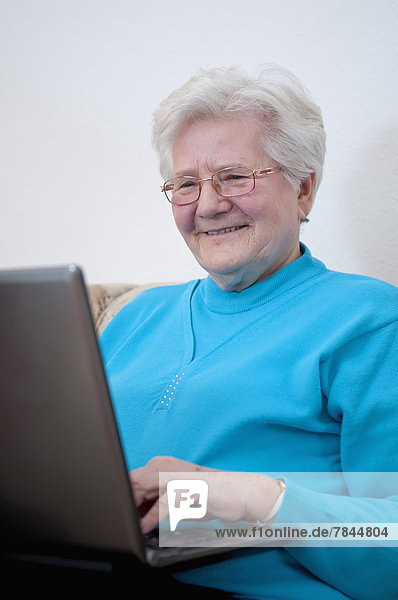 Seniorin bei der Arbeit am Laptop  lächelnd