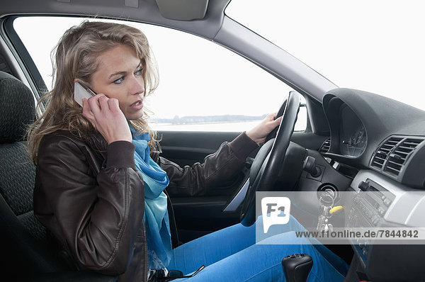 Woman talking on mobile phone in car