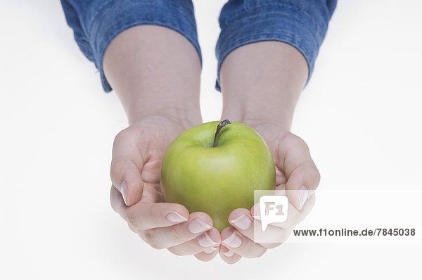 Human hands holding green apple against white background  close up