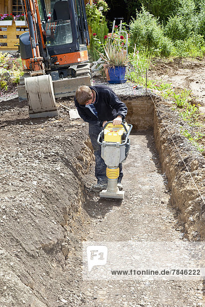 Europe  Germany  Rhineland Palatinate  Man working with soil compactor during house building