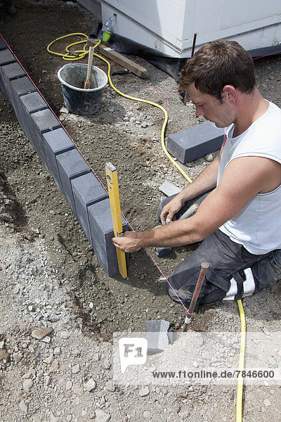 Deutschland  Rheinland-Pfalz  Arbeiter beim Verlegen von Pflastersteinen im Erdreich