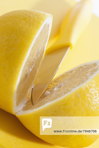 Zitrone mit Messer auf Kunststoffplatte  Nahaufnahme