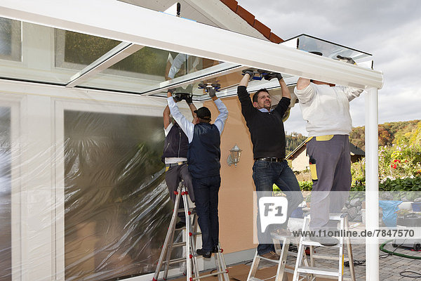 Deutschland  Rheinland-Pfalz  Männer montieren Glasvordach