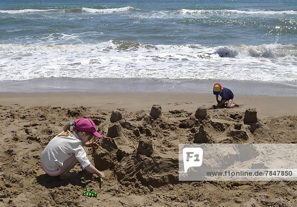 Spanien  Mädchen und Junge spielen am Strand im Sand