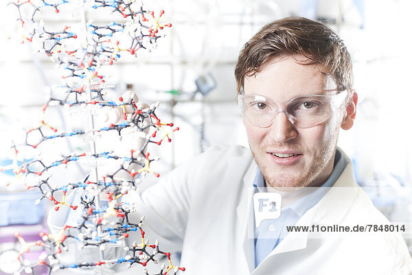 Germany  Portrait of young scientist with DNA model  smiling