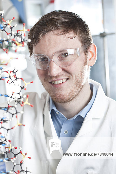 Germany  Portrait of young scientist with DNA model  smiling