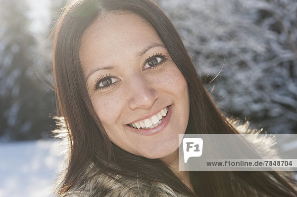 Österreich  Salzburg  Portrait einer jungen Frau im Schnee  lächelnd