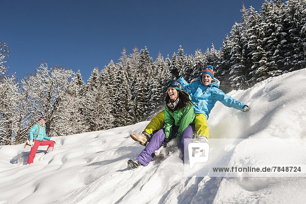 Austria  Salzburg  Young man and women with sledge in snow at Altenmarkt Zauchensee
