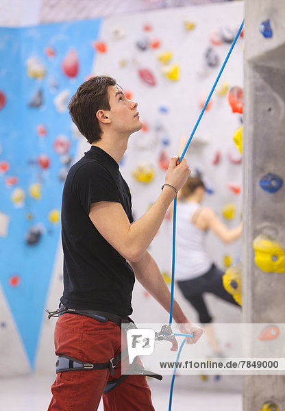 Man preparing for bouldering while woman in background
