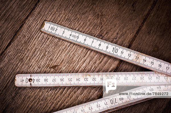 Old folding ruler on wooden background  close up