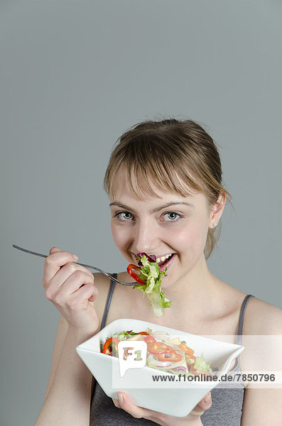 Portrait of young woman eating salad  close up