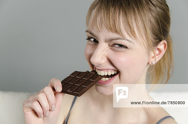 Porträt einer jungen Frau beim Schokoladenessen  lächelnd