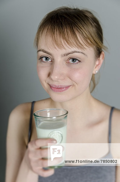 Porträt einer jungen Frau mit einem Glas Milch  lächelnd
