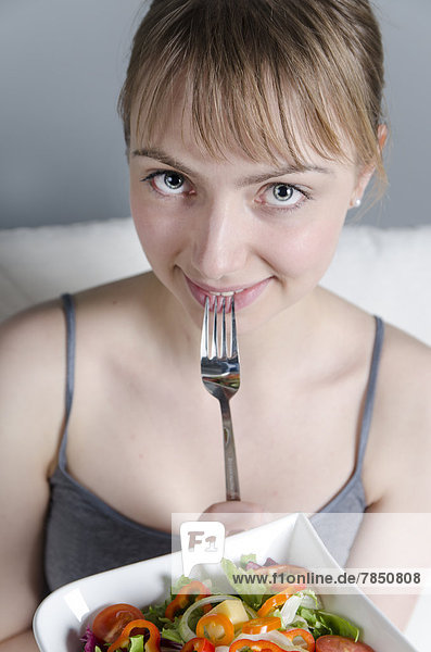 Portrait of young woman holding salad bowl  close up