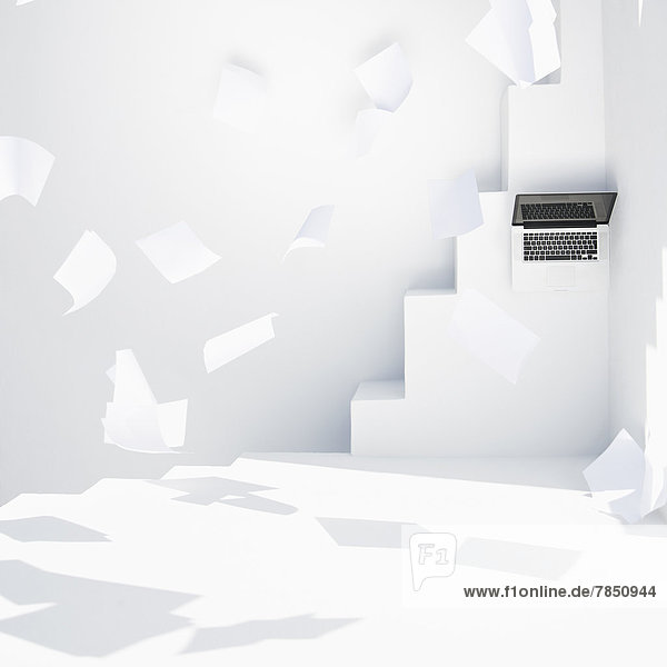 Laptop and flying papers on white modern stairs