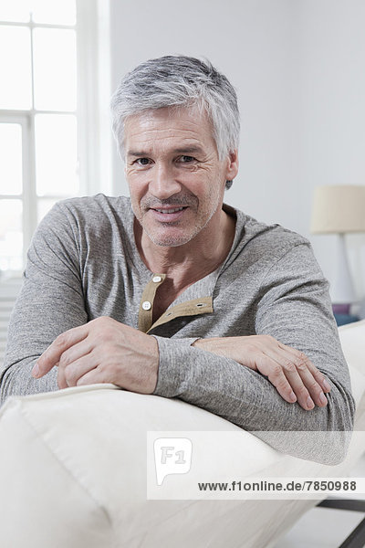 Portrait of mature man sitting on couch  smiling