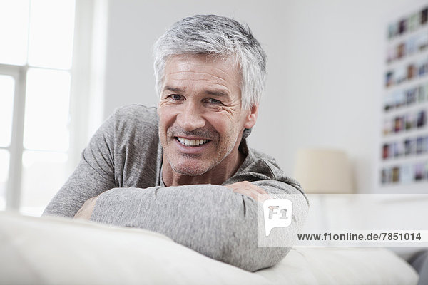 Porträt eines reifen Mannes auf der Couch sitzend  lächelnd