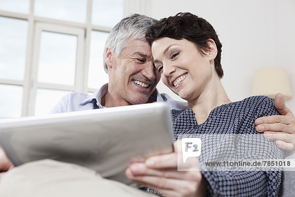 Germany  Bavaria  Munich  Couple using digital tablet at home  smiling