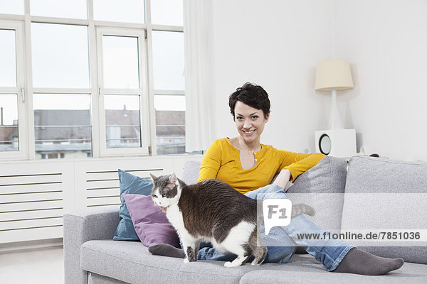 Portrait of mid adult woman with cat on couch  smiling