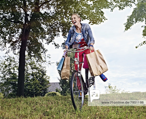 Junge Frau auf dem Fahrrad mit Einkaufstaschen