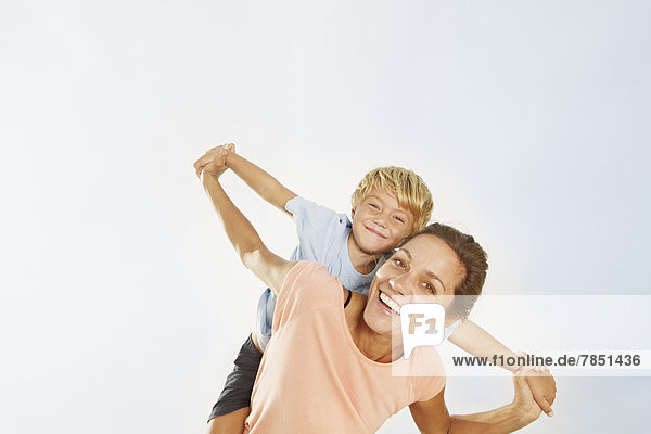 Spain  Mother giving piggy back ride to son  smiling