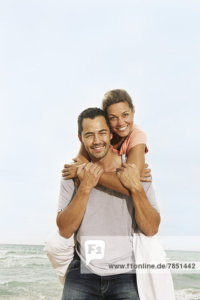 Spain  Mid adult man giving piggy back ride to woman  smiling