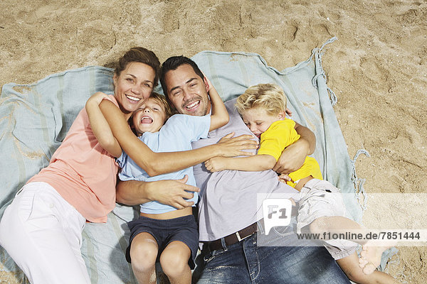 Spain  Family lying on beach at Palma de Mallorca  smiling