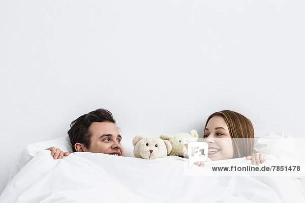 Young couple with teddy bear looking at each other  smiling