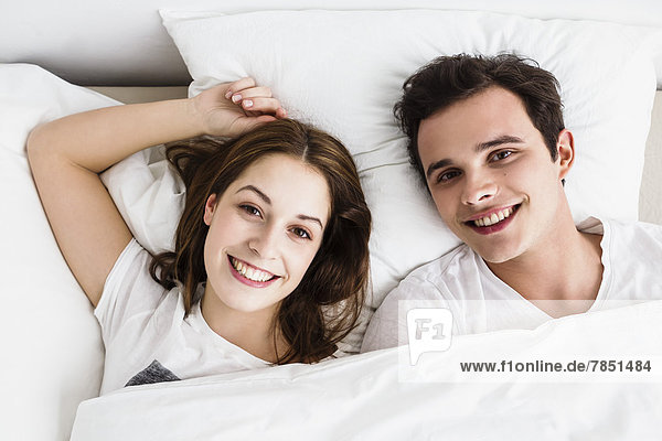 Junges Paar auf dem Bett liegend  lächelnd