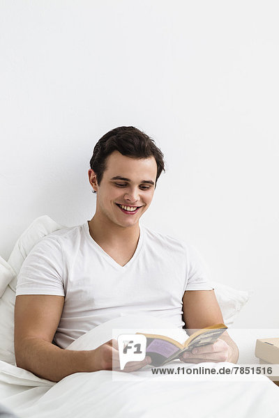 Young man reading book  smiling