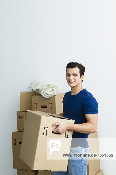 Porträt eines jungen Mannes mit Kartonschachtel  lächelnd