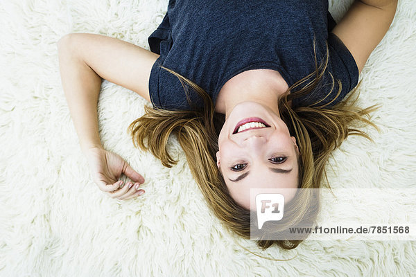Portrait of young woman lying on carpet  smiling
