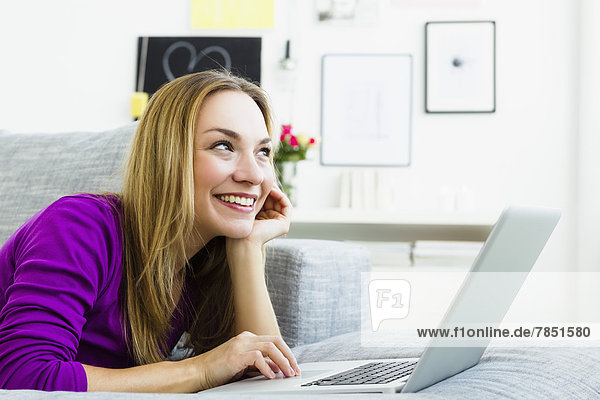 Young woman using laptop  looking away