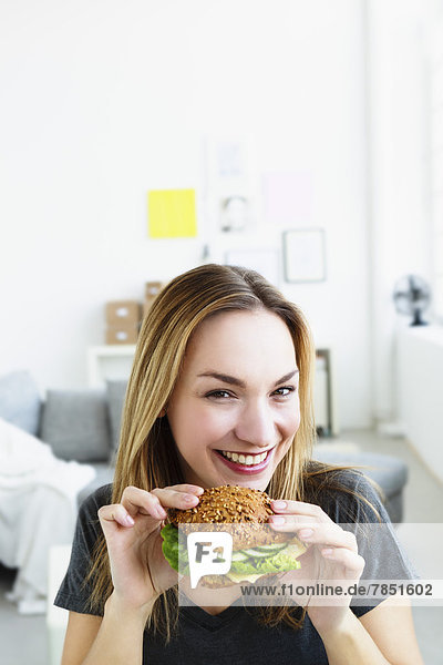 Portrait of young woman holding burger  smiling