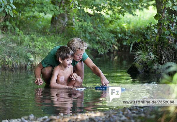 Austria Friends playing with boat in stream smiling