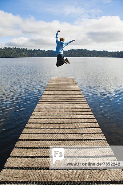 Woman jumping on a jetty at Lake Ianthe  West Coast  South Island  New Zealand  Pacific
