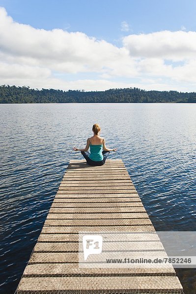 Woman meditating on a jetty  Lake Ianthe  West Coast  South Island  New Zealand  Pacific